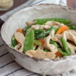 Chicken asparagus stir fry with carrots and snow peas in a bowl.