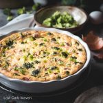 Broccoli cheddar quiche with bacon in a white quiche dish with scalloped edge.
