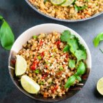 A bowl and a pan full of cauliflower fried rice on a dark background
