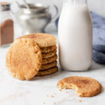 keto snickerdoodle cookies with cinnamon stacked by a bottle fo milk